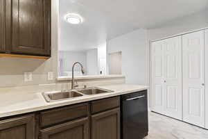 Kitchen featuring dark brown cabinetry, sink, and black dishwasher