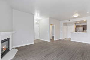 Unfurnished living room featuring dark hardwood / wood-style flooring and a chandelier