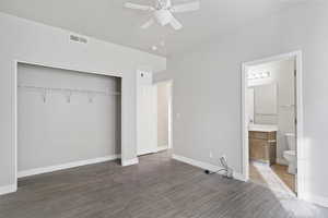 Unfurnished bedroom featuring dark wood-type flooring, a closet, ceiling fan, and ensuite bathroom