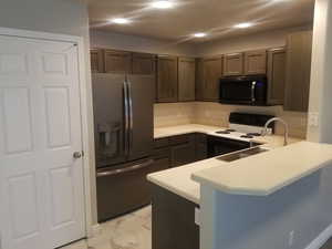 Kitchen featuring stainless steel fridge with ice dispenser, kitchen peninsula, range with electric stoveto