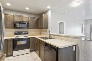 Kitchen featuring dishwasher, sink, kitchen peninsula, and white range with electric cooktop