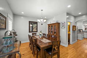 Dining room with ornate columns, a chandelier, and light hardwood / wood-style flooring