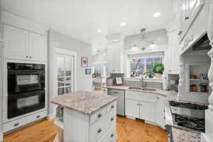 Kitchen featuring pendant lighting, white cabinetry, stainless steel appliances, decorative backsplash, and sink