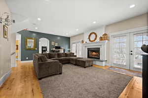 Living room featuring light wood-type flooring, french doors, and a brick fireplace