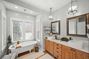 Bathroom with hardwood / wood-style flooring, a bath, a chandelier, and vanity