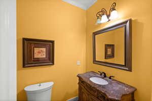 Bathroom with toilet, vanity, and ornamental molding