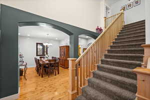 Stairs with an inviting chandelier and hardwood / wood-style floors