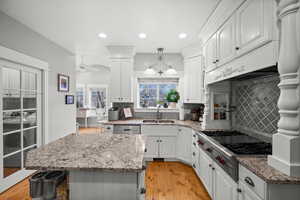 Kitchen featuring white cabinets, a center island, stainless steel appliances, decorative backsplash, and sink