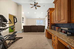 Exercise room featuring ceiling fan, lofted ceiling, light carpet, and built in desk