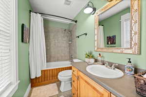 Full bathroom featuring toilet, shower / tub combo with curtain, tile patterned flooring, a wealth of natural light, and vanity