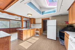 Kitchen featuring tile countertops, a skylight, white refrigerator, and light hardwood / wood-style floors