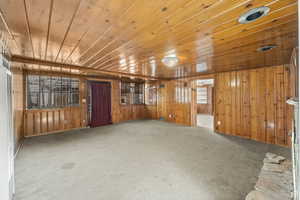 Carpeted spare room with wood ceiling