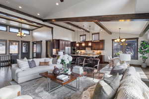 Living room with beam ceiling, light wood-type flooring, a high ceiling, and an inviting chandelier