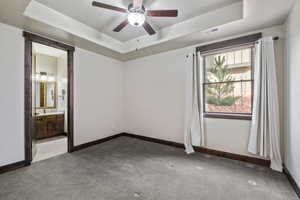 Spare room featuring ceiling fan, carpet floors, and a tray ceiling