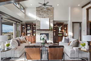 Living room with ceiling fan, a towering ceiling, and a fireplace