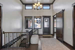 Foyer with a barn door, a wealth of natural light, and an inviting chandelier