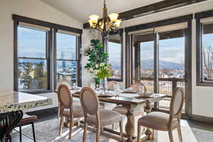 Dining space with a mountain view, plenty of natural light, vaulted ceiling, and a notable chandelier