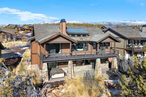 Rear view of house featuring a deck with mountain view and a hot tub