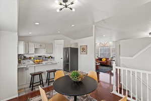 Dining room with sink, hardwood / wood-style floors, lofted ceiling, and a notable chandelier