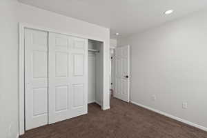 Unfurnished bedroom featuring a closet and dark colored carpet