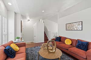 Living room with a healthy amount of sunlight, vaulted ceiling, and hardwood / wood-style flooring