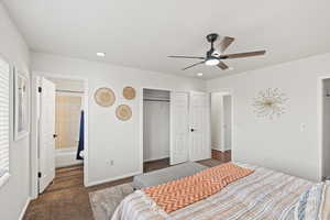 Carpeted bedroom featuring ceiling fan, connected bathroom, a closet, and multiple windows