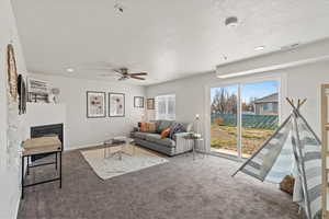 Carpeted living room featuring ceiling fan and a textured ceiling