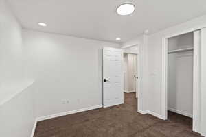 Unfurnished bedroom with a closet and dark carpet