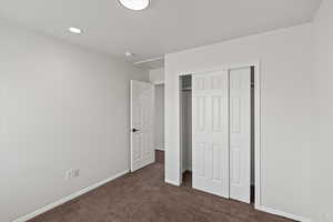 Unfurnished bedroom with dark carpet and a closet