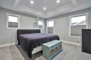 Carpeted bedroom with a tray ceiling