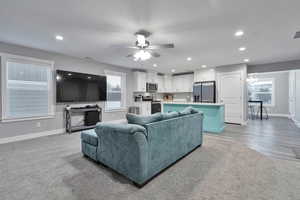 Living room with ceiling fan and light colored carpet