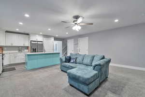 Living room featuring light carpet, ceiling fan, and sink