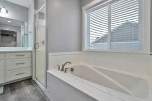 Bathroom featuring shower with separate bathtub, hardwood / wood-style floors, and vanity