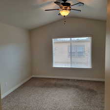 Spare room featuring carpet flooring, lofted ceiling, and plenty of natural light