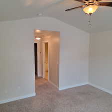 Spare room featuring vaulted ceiling, light colored carpet, and ceiling fan