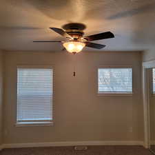 Unfurnished room featuring carpet, ceiling fan, and a textured ceiling