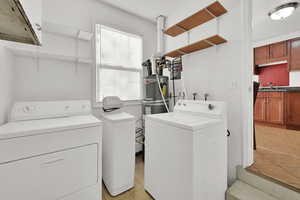 Clothes washing area with a healthy amount of sunlight, independent washer and dryer, and gas water heater