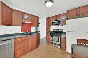 Kitchen with light tile patterned flooring, stainless steel appliances, and sink