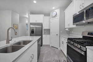 Kitchen with sink, stainless steel appliances, and white cabinets