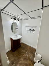 Bathroom with a paneled ceiling, concrete floors, and vanity