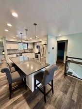 Kitchen with pendant lighting, appliances with stainless steel finishes, a kitchen island, decorative backsplash, and sink