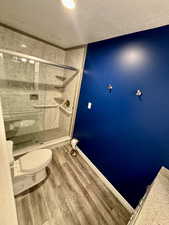 Master Bathroom featuring toilet, a shower with shower door, and hardwood / wood-style floors