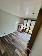 Empty room with a textured ceiling and dark wood-type flooring