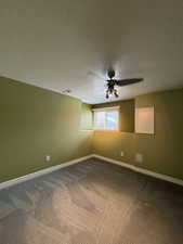 Carpeted empty room with ceiling fan and a textured ceiling