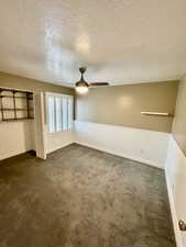 Unfurnished bedroom featuring ceiling fan, a textured ceiling, a closet, and dark colored carpet