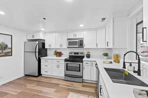 Kitchen featuring sink, white cabinets, light hardwood / wood-style flooring, and stainless steel appliances