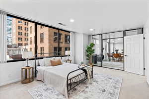 Carpeted bedroom featuring floor to ceiling windows