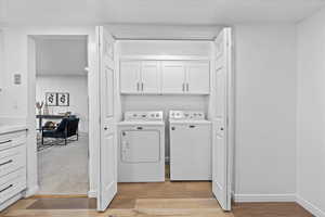 Laundry room with cabinets, separate washer and dryer, and light carpet