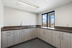 Kitchen featuring light brown cabinetry, dark tile patterned flooring, and sink