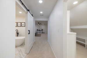 Corridor featuring a barn door and light colored carpet